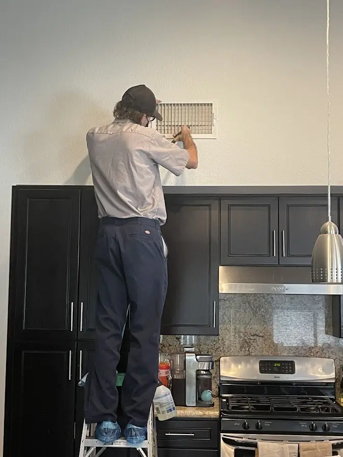 Technician inspecting an air vent during HVAC service in Oakland Park